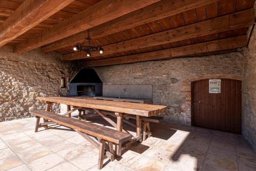 a wooden table and bench in a room with a stove at Casa Rural Moixella in Lladurs