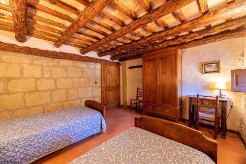 a bedroom with two beds and a table and a desk at Casa Rural Moixella in Lladurs