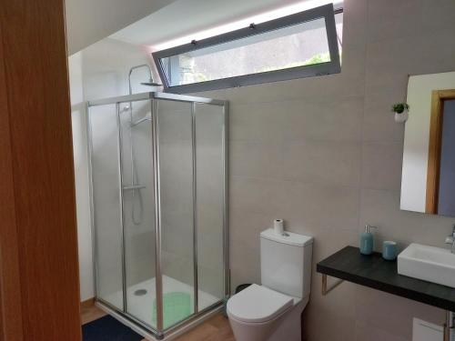 a bathroom with a shower and a toilet and a window at Refúgio de Pedra in Fajã da Ovelha