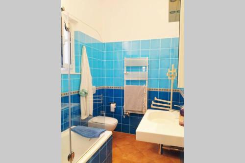 baño de azulejos azules con lavabo y aseo en CasaViva - Beautiful Bilo with shared pool in Genova Nervi en Génova