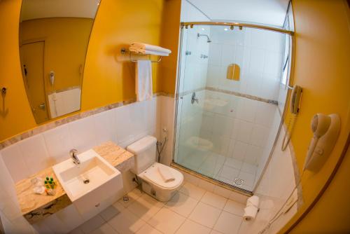 a bathroom with a shower and a toilet and a sink at Favorita Golden Hotel e Eventos in São José