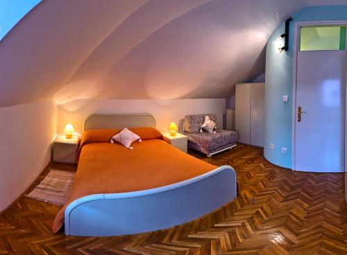 a bedroom with an orange bed and a chair at Villa Šoulavy in Kaštela