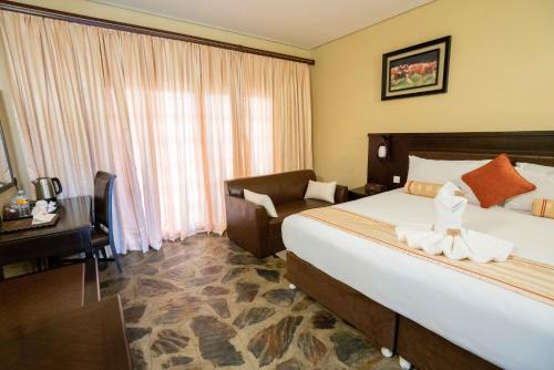 a hotel room with a bed and a chair and a window at Big Valley Game Lodge in Lobatse