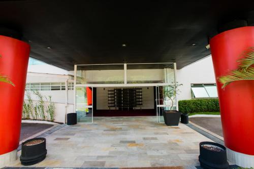 a large glass building with red columns in front of it at Favorita Golden Hotel e Eventos in São José