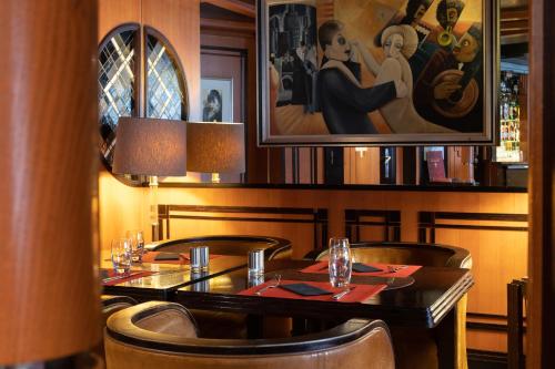 a table in a restaurant with a painting on the wall at Hotel Du Parc - Mulhouse Centre in Mulhouse