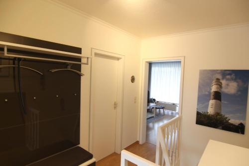 a room with a staircase with a lighthouse picture on the wall at Calma 1 ebenerdig in Wenningstedt
