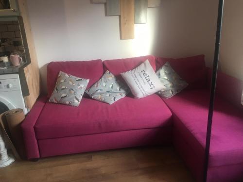 eine rosa Couch mit Kissen darauf im Zimmer in der Unterkunft Driftwood Loft in Killyleagh