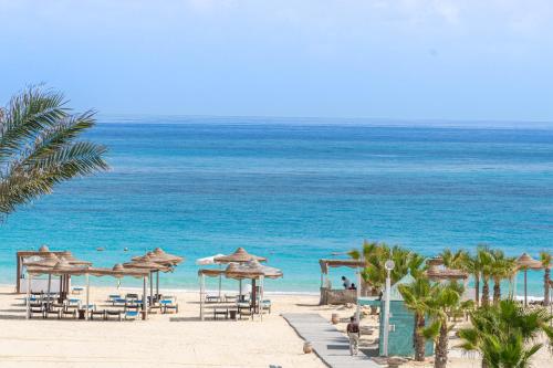 a beach with chairs and umbrellas and the ocean at Caesar Bay Resort in Marsa Matruh