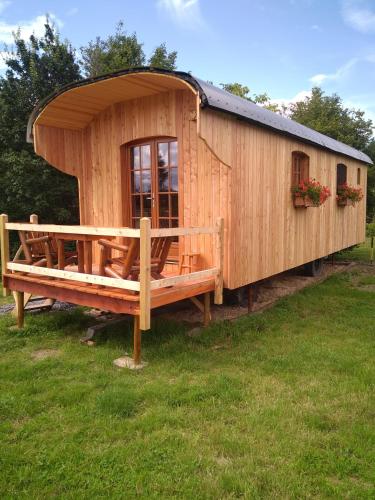 a large wooden cabin with a bench in the grass at Au Paradou du Bûcheron Adults only in Lessive