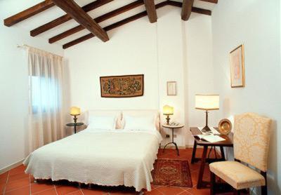 a bedroom with a white bed and a desk and a chair at Agriturismo Alla Cedrara in Ferrara