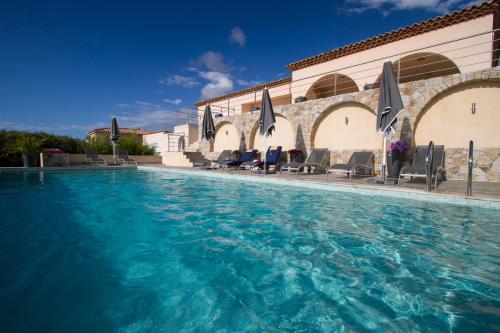 uma piscina com cadeiras e guarda-sóis ao lado de um edifício em Villa la Vista em Lumio