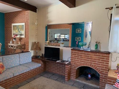 Una sala de estar con chimenea de ladrillo y televisión. en Lindo Sobrado Amarelo -próximo a praia, en Mongaguá