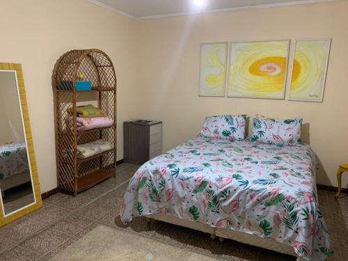 ein Schlafzimmer mit einem Bett und einem Kleiderständer in der Unterkunft Lindo Sobrado Amarelo -próximo a praia in Mongaguá