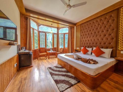 a bedroom with a large bed in a room with windows at Hotel Mountain Top in Manāli