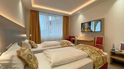ein Hotelzimmer mit 2 Betten und einem TV in der Unterkunft Hotel Danner in Rheinfelden
