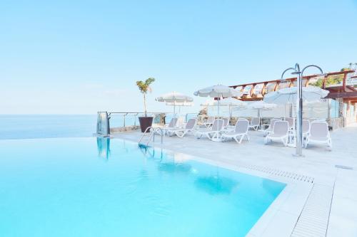 a swimming pool with chairs and umbrellas next to the ocean at Gloria Palace Amadores Thalasso & Hotel in Puerto Rico de Gran Canaria