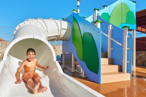a young boy sliding down a water slide at a water park at Gloria Palace Amadores Thalasso & Hotel in Puerto Rico de Gran Canaria