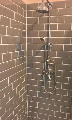 a shower in a bathroom with a brick wall at Hayes Suite in Oswestry