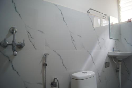 biała łazienka z toaletą i umywalką w obiekcie Cornerbunker w mieście Mysuru