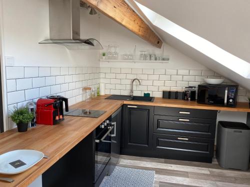 une cuisine avec des armoires noires et un comptoir en bois dans l'établissement A la tête de Cheval, à Épernay