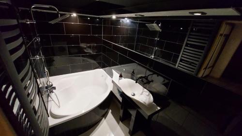 a bathroom with a white sink and black tiled walls at Domek nad jeziorem in Koszajny