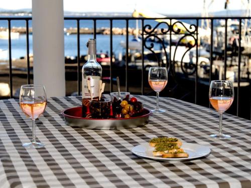 a table with two glasses of wine and a plate of food at Residence Farenc vue sur la lagune in Marseillan