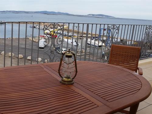 a wooden table on a balcony with a view of the ocean at Residence Farenc vue sur la lagune in Marseillan