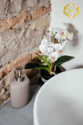 a white bottle of soap and a vase of flowers at VenuSuite VENOSA - Luxury House, Spa & Relax - in Venosa