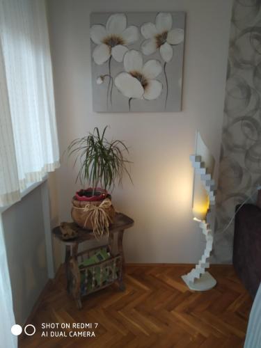 a living room with a table and a flower painting on the wall at Apartman Ivan in Vrdnik