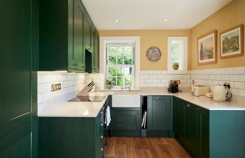 a kitchen with green cabinets and white counter tops at Balcarres East Lodge in Colinsburgh