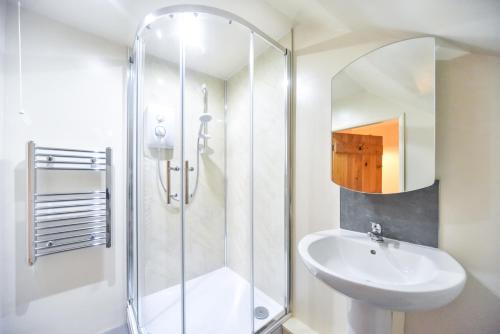a white bathroom with a sink and a shower at Chatterbox Cottage in Wirksworth