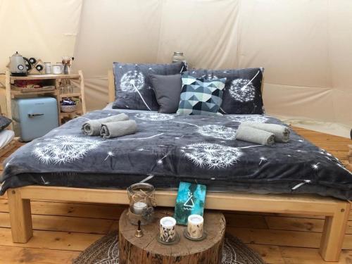 a bed with a blue comforter and pillows on it at Glamping Nad Meandry in Unhošť
