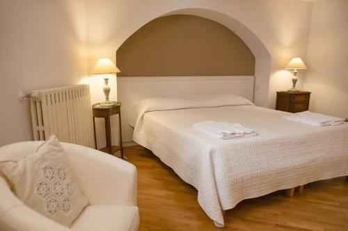 a bedroom with a white bed and a chair at La Casa di Ele in Matera