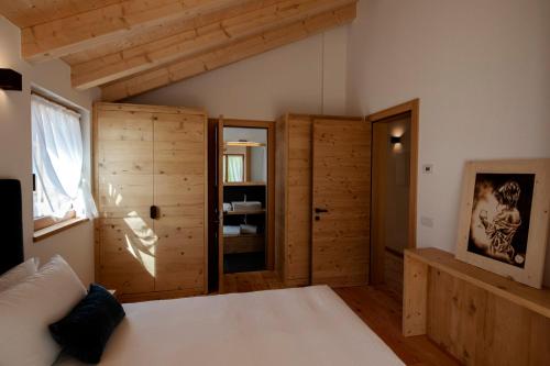 a bedroom with a white bed and wooden walls at Chalet del Capriolo in Vodo Cadore