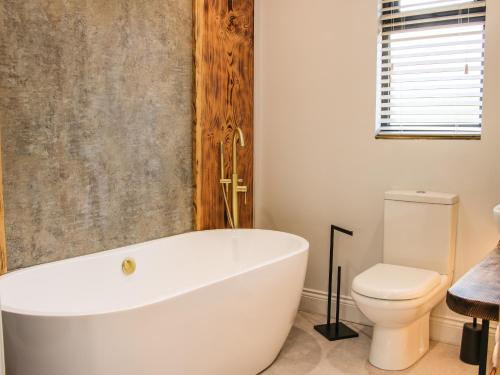 a bathroom with a white tub and a toilet at Meadow View in Meifod
