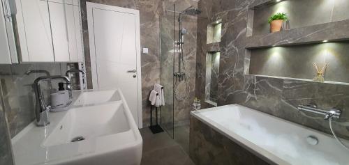 La salle de bains est pourvue d'un lavabo blanc et d'une douche. dans l'établissement Aquamarine Deluxe Apartment, à Dubrovnik