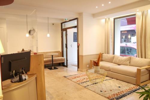 a living room with a couch and a tv at Little H&ocirc;tel in Paris