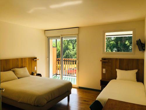 a bedroom with two beds and a balcony at Logis Hôtel Les TILLEULS in Bruère-Allichamps
