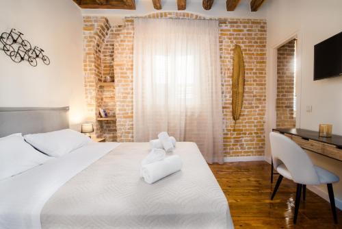 a bedroom with a large white bed and a desk at Curcumelli Luxury Suites - Κorkira in Corfu
