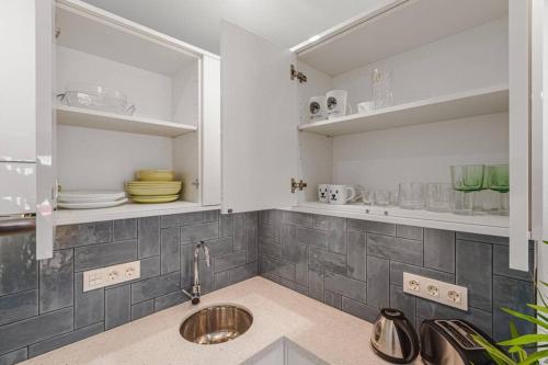 a kitchen with white cabinets and a sink at Tenerife Royal Gardens One Bedroom Apartment in Playa de las Americas