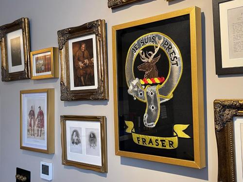 a wall of framed pictures on a wall at Pamper yourself in our DOUBLE SIZED copper tub -2 bedroom villa in Inverness