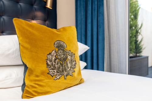 a yellow pillow with a bird on it sitting on a bed at Pamper yourself in our DOUBLE SIZED copper tub -2 bedroom villa in Inverness
