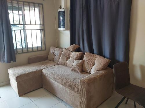 a brown couch in a living room with a window at Waterland Suites in Paramaribo