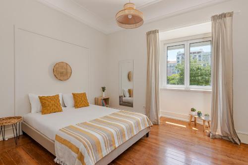 a white bedroom with a bed and a window at The Local Guest House Lisbon in Lisbon