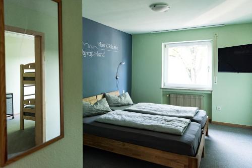 Schlafzimmer mit einem Bett, einem Spiegel und einem Fenster in der Unterkunft Hotel Check-Rhein - Self Check-in in Neuenburg am Rhein