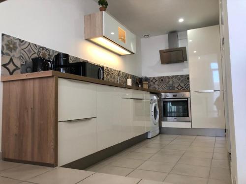 une cuisine avec des armoires blanches et une laveuse et une sécheuse dans l'établissement Residence Provence plage, à La Ciotat