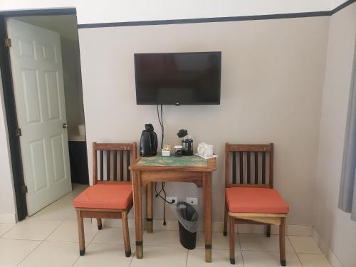 a table with two chairs and a television on a wall at Casa Vistas del Rio in Sámara