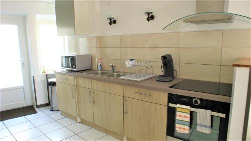 une cuisine avec un évier et un micro-ondes dans l'établissement Maison de charme et confort, à Gannat