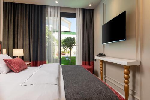 a hotel room with a bed and a flat screen tv at Motif Hotel Çeşme in Cesme