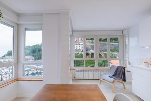 a kitchen with a table and chairs and windows at Portua - Baskey Rentals in Mutriku